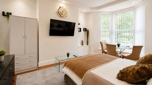 Une chambre à coucher moderne, équipée d’un lit, d’une télévision, d’un bureau et d’une chaise.