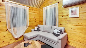 A cozy room with a sectional sofa, wooden walls, and a framed welcome sign. - Cozy Onalaska Cabin ~ 2 Mi to Lake Livingston! (Onalaska)