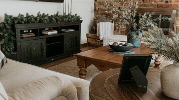 Ein gemütliches Wohnzimmer mit Kamin, Wandfernseher und bequemer Couch.