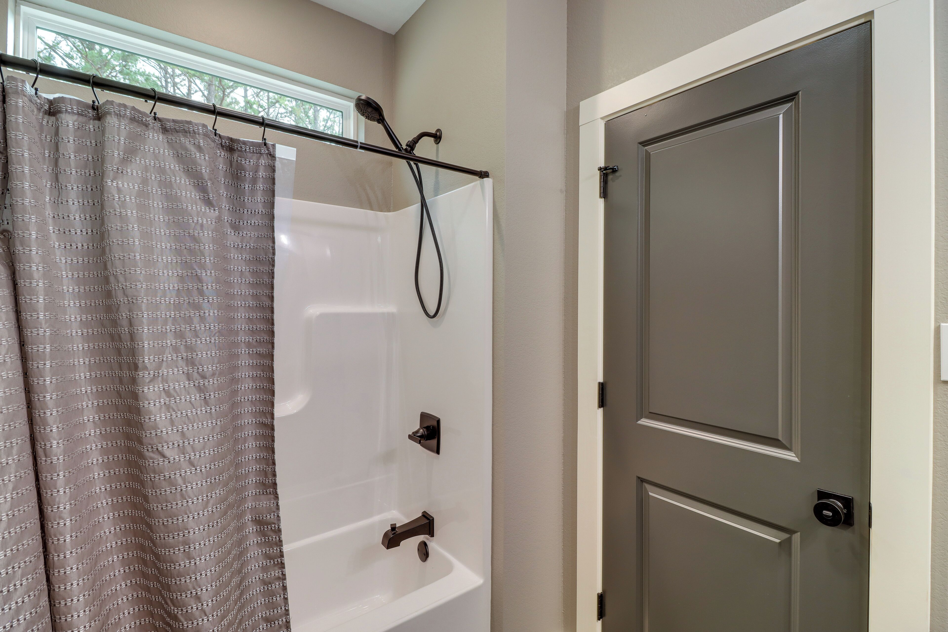 A bathroom with a shower, a bathtub, and a door.