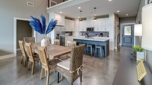 Una cocina moderna con armarios blancos, una isla central e iluminación colgante.