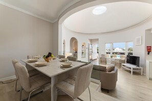 A modern dining area with a table set for four, a television, and a view of the outdoors. - Villa Alisa - Three Bedroom Villa, Sleeps 6 (Tías)