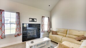 A living room with a fireplace, a sofa, a coffee table, and curtains. - Cape Charles Home: 4 Mi to Kiptopeke State Park! (Cape Charles)