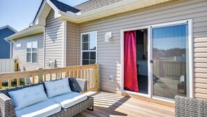 A covered deck with a wicker sofa and a wooden railing. - Cape Charles Home: 4 Mi to Kiptopeke State Park! (Cape Charles)
