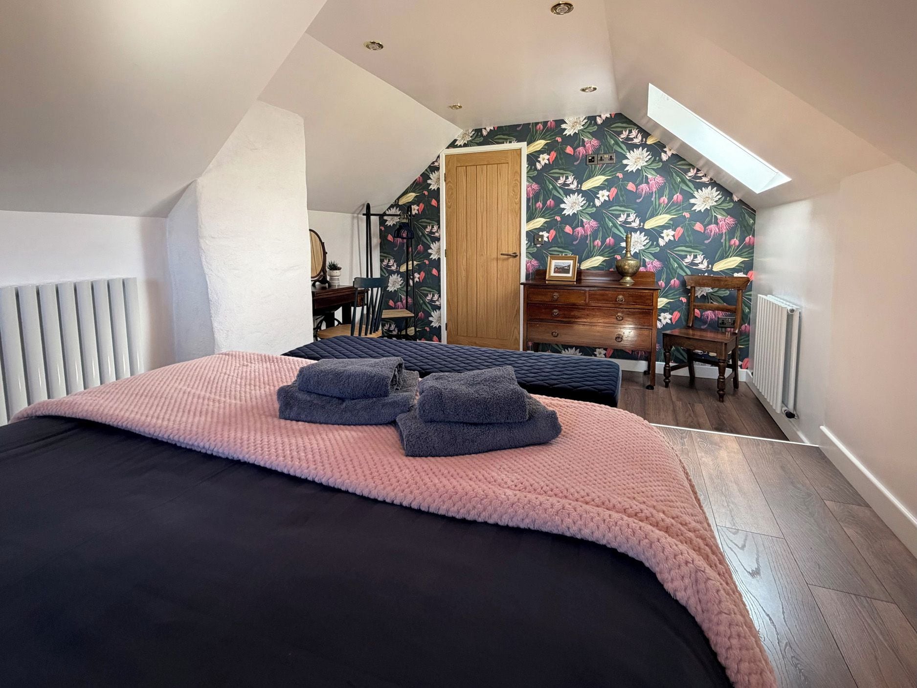 Un dormitorio con cama, cómoda, silla y escritorio.