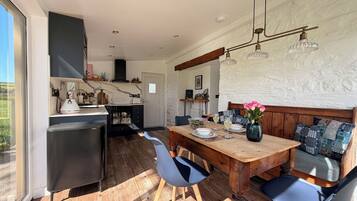 Une cuisine moderne avec un coin repas, des meubles en bois et une vue dégagée sur l’extérieur grâce à une grande fenêtre.