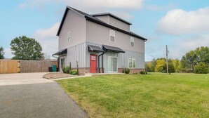 Une maison à deux étages avec une porte rouge, un porche abrité et une pelouse bien entretenue.