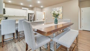 Un coin repas avec une table en bois et quatre chaises rembourrées, un vase de fleurs et un tableau accroché au mur.