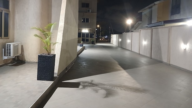 Un passadís nocturn amb sòl de rajoles, una planta en test i un aire condicionador fixat a la paret.