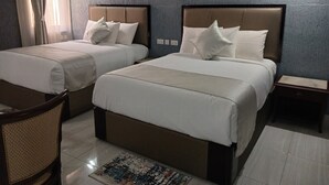 Habitació d'hotel amb dos llits, una taula petita i una cadira.