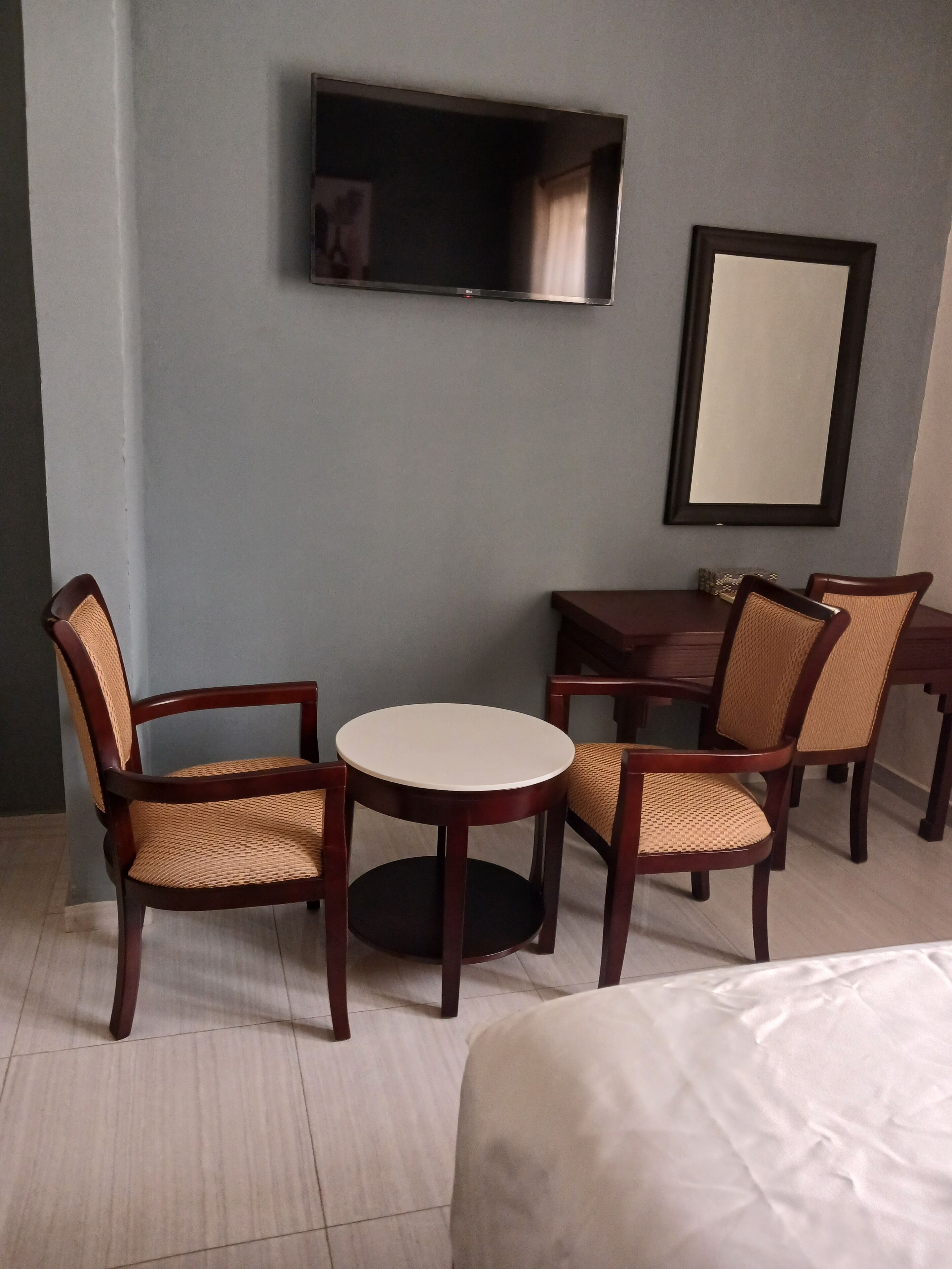 Une chambre d’hôtel avec un lit, une table ronde, deux chaises, un téléviseur fixé au mur et un grand miroir.
