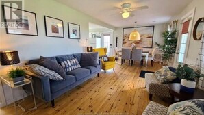 Een woonkamer met een bank, fauteuils, een eettafel en een plafondventilator.