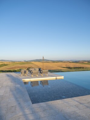A pool with a view of rolling hills and a distant tower. - Villa Tosca (Peccioli)