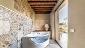 A modern bathroom with a freestanding bathtub, patterned tiles, and a view to the outside. - Villa Tosca (Peccioli)