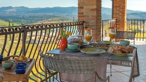 A terrace with a table set for breakfast, overlooking a mountainous landscape. - Villa Tosca (Peccioli)