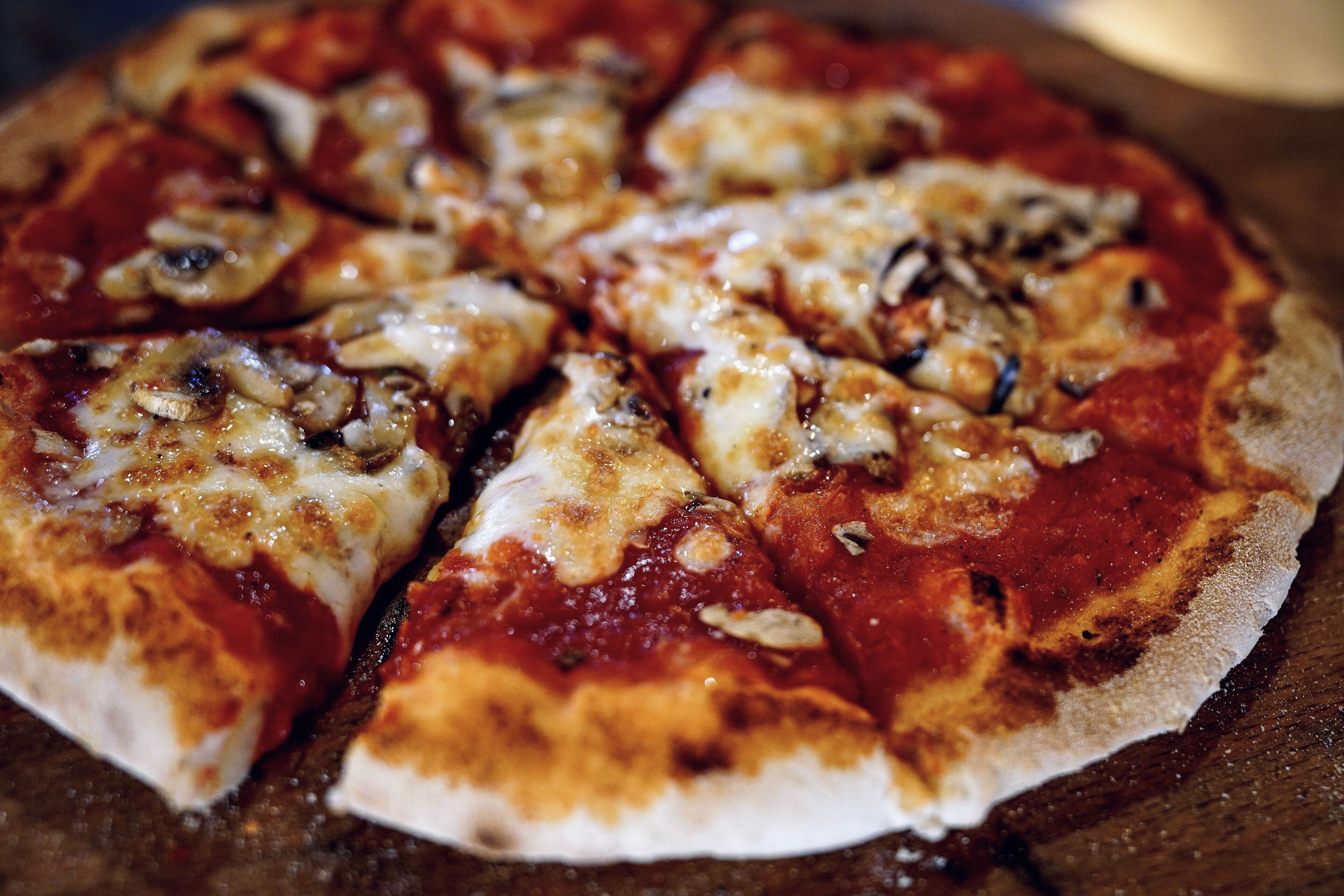 A pizza with cheese and mushrooms on a wooden surface.