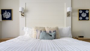 A neatly made bed with a white quilt, two pillows, and a blue accent pillow. There are two wall-mounted lamps on either side of the bed. - Spectacular Ocean View - Heated 80° Pool - Seascape (Aptos)