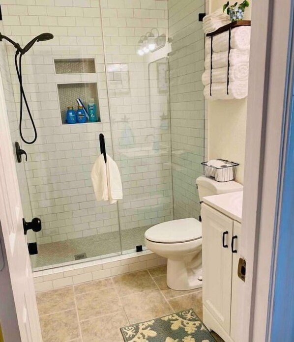 A bathroom with a glass-enclosed shower, a toilet, and a sink with a towel rack. - Cozy DFW Duplex, central location, kids, pets (North Richland Hills)