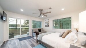 A bedroom with a bed, a ceiling fan, a sofa, and a TV on the wall. - Luxury Lakefront Escape, Beach Volleyball, Kayaks, Fire Pit Hot Tub & Game Room! (Hot Springs)