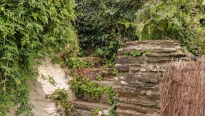 A stone staircase surrounded by dense greenery and a wire fence. - Alexander's Cottage (Kingsbridge)