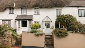 A traditional white building with a thatched roof, a small front door, and a staircase leading to the entrance. - Alexander's Cottage (Kingsbridge)