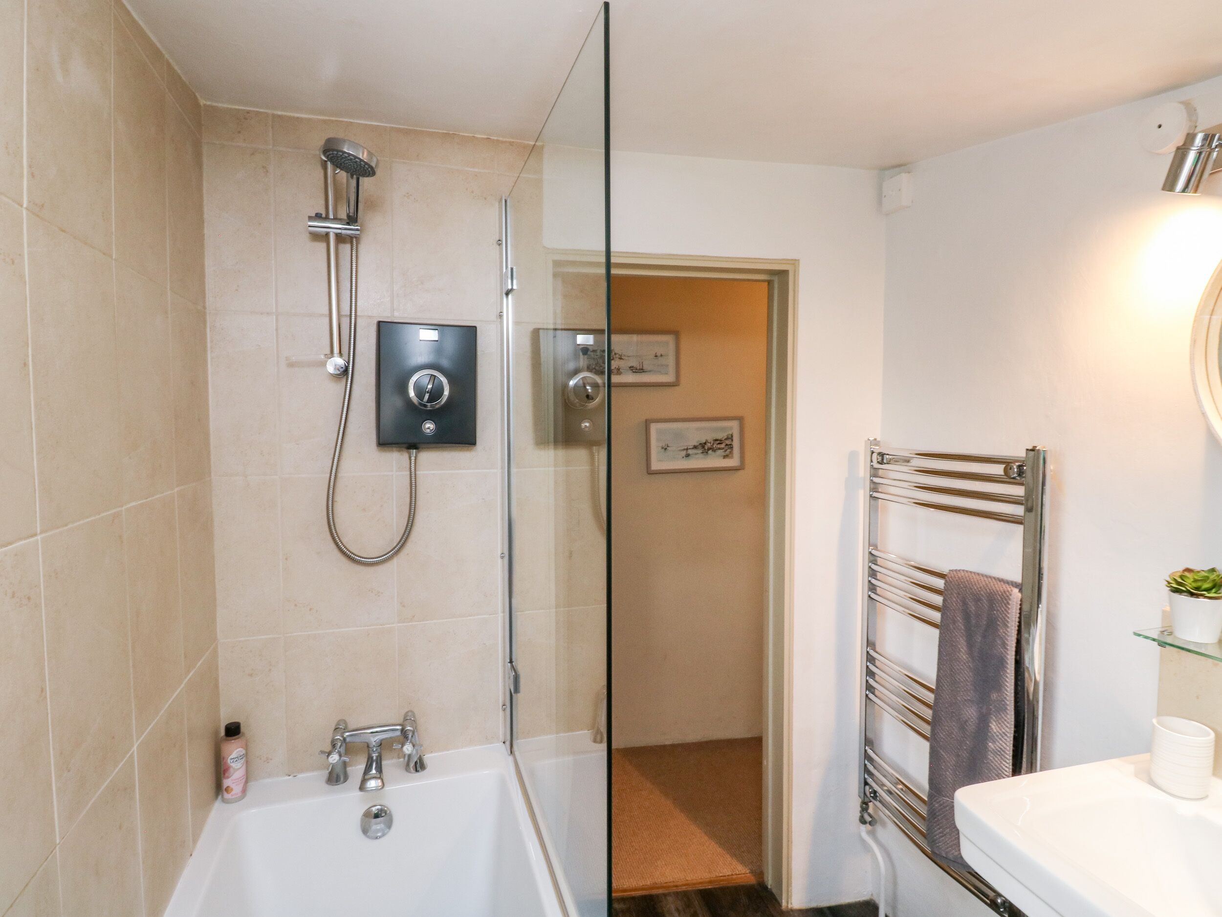 Une salle de bain moderne avec une douche à l’italienne, une baignoire blanche et une porte de douche en verre.