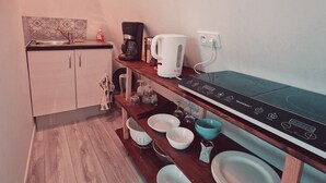 A compact kitchen with a sink, coffee maker, kettle, and a stove. - Location Saisonnière, Meublée, Appartement Type Studio à Sèvres (Sèvres)