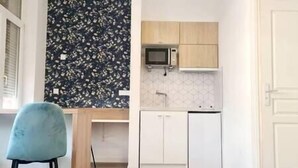 Une cuisine de taille réduite, équipée d’un four à micro-ondes, de meubles blancs et d’un crédence décorée.