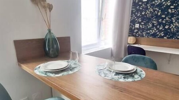 Une table à manger avec deux chaises, un vase et un élément décoratif mural.