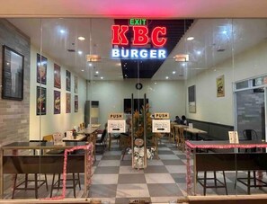 Step into KBC Burger for a casual dining experience with tables set up for a meal and framed pictures on the walls.
