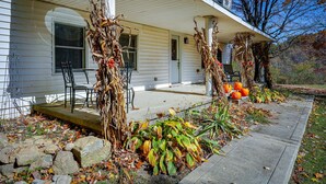 Une maison dotée d’un porche décoré de feuilles d’automne et de citrouilles.