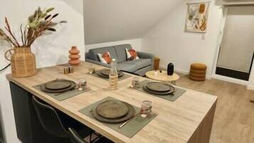A dining area with a long table set for four, a sofa, and a small round table in a modern apartment.