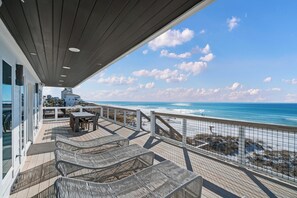 A deck with outdoor seating overlooking the ocean.