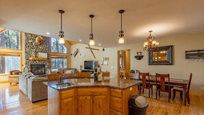 Una cocina espaciosa con una isla grande, armarios de madera y una chimenea de piedra.