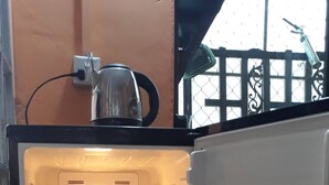 Een open koelkast met een waterdispenser bovenop, een bedieningspaneel en een draaiknop voor de temperatuur.