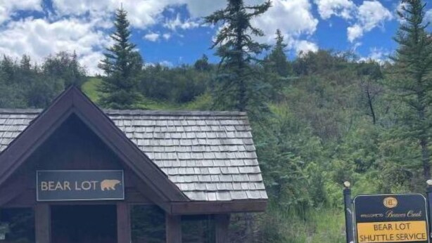 A small wooden cabin labeled "Bear Lot" with a sign indicating shuttle service and parking information. - Eagle River Retreat (Avon)