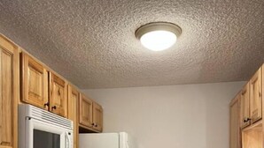 A compact kitchen with wooden cabinets, a microwave, a refrigerator, an oven, and a sink. - Eagle River Retreat (Avon)