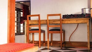 A room with a wooden table and two chairs, a red sofa, and a checkered floor. - Lushoto Views Cottage (Lushoto)