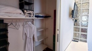 A walk-in closet with a bed, shelves, and a mirror. - Casa Flora (Taranto)