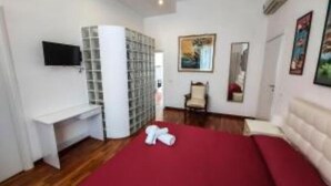 A hotel room with a bed, a desk, a chair, and a TV on the wall. - Casa Flora (Taranto)