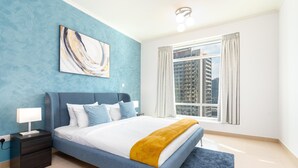Une chambre à coucher avec un lit, une table de chevet, une lampe, une fenêtre avec des rideaux et une vue sur la ville.