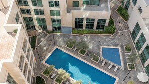 Une piscine sur le toit, entourée de chaises longues et de verdure, avec des bâtiments en arrière-plan.