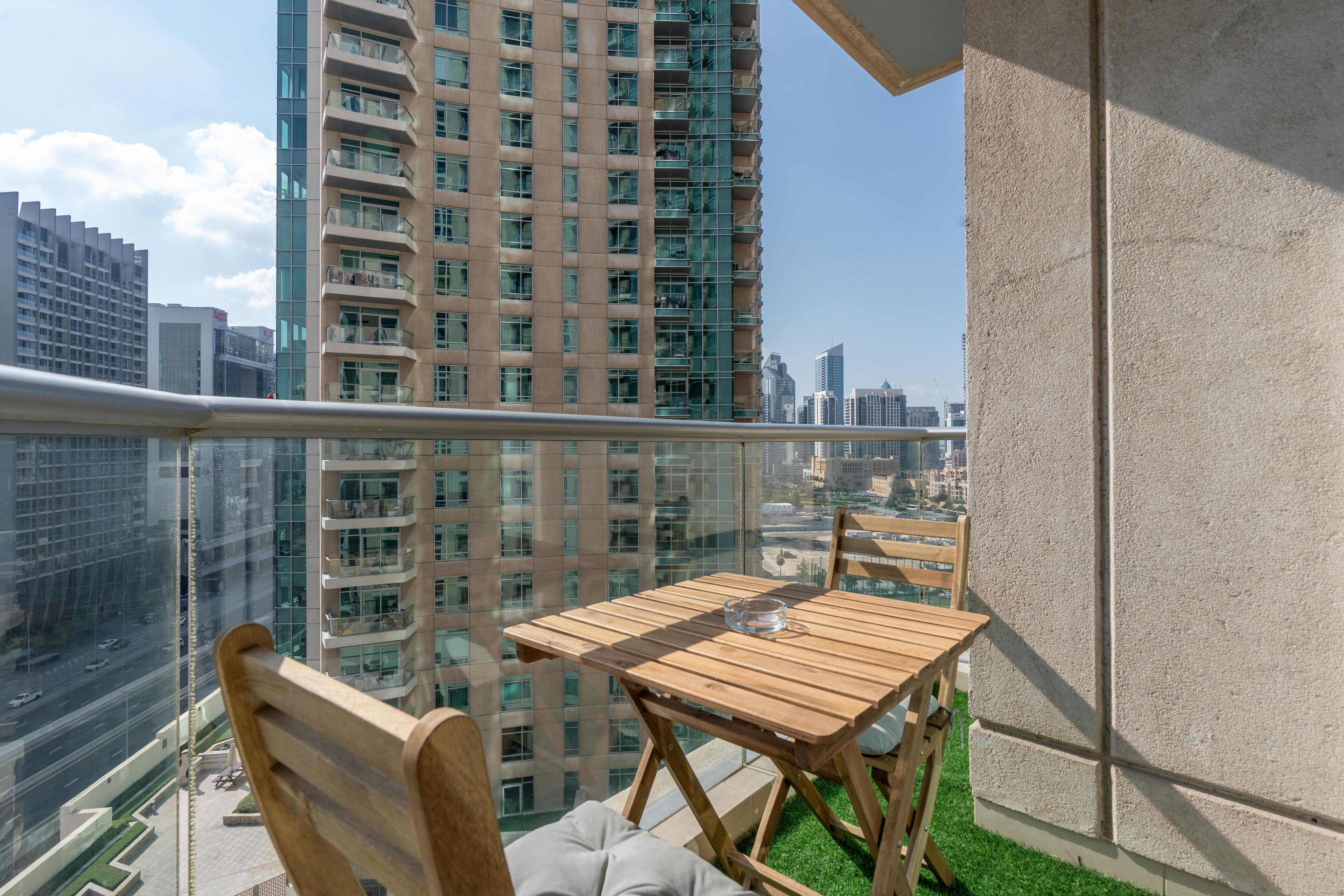 Ein Balkon mit Holztisch und Stühlen, mit Blick auf eine Skyline mit Hochhäusern.