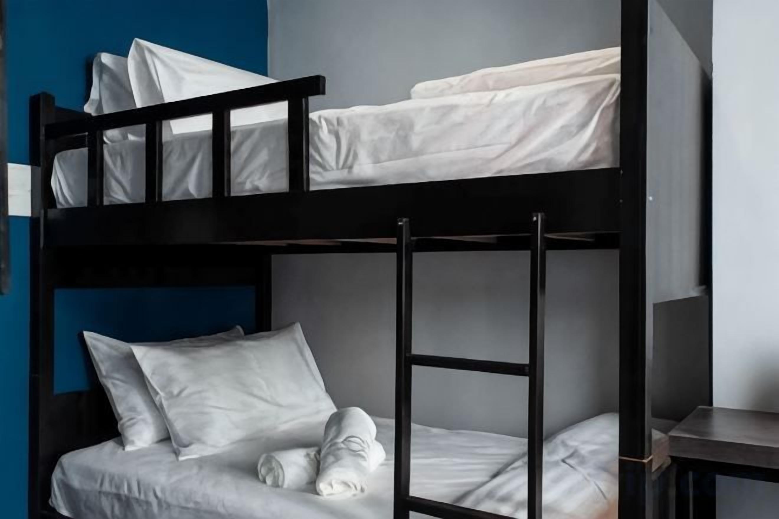 Een stapelbed met witte beddengoed en kussens, een ladder en een klein tafeltje ernaast.