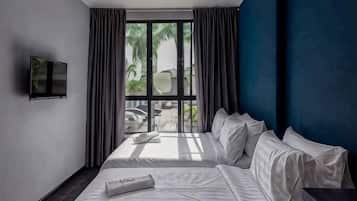 A hotel room with a large bed, a flat-screen TV mounted on the wall, and a view of the outdoors.