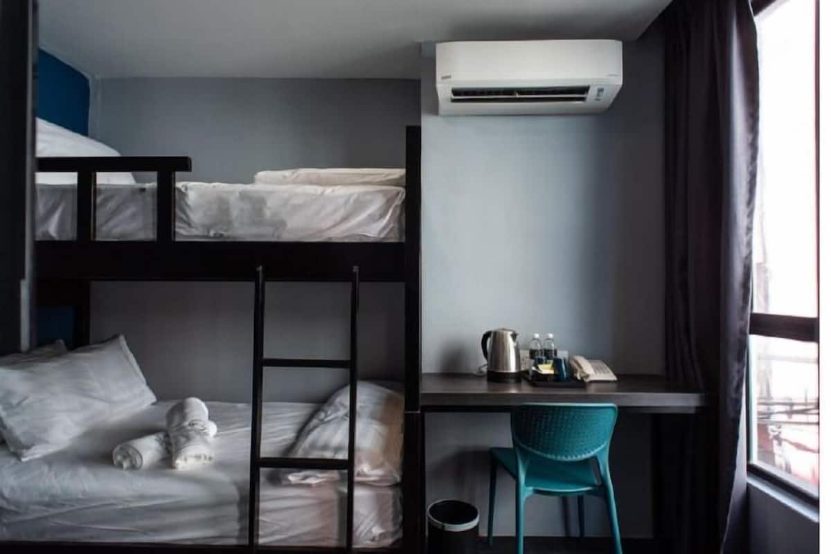 A bunk bed room with a desk, air conditioning unit, and a window.