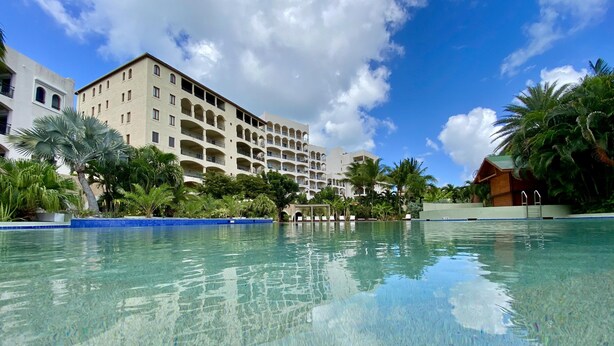 A hotel with a large pool, multiple balconies, and lush greenery. - 2-bed Designer Apartment Sleeps 4, Resort Pool (Lowlands)