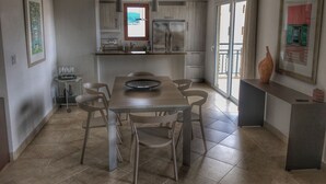 A modern kitchen with a dining area, featuring a large table, chairs, and a refrigerator. - 2-bed Designer Apartment Sleeps 4, Resort Pool (Lowlands)