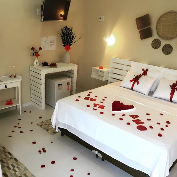 Una habitación de hotel con una cama, un escritorio, un refrigerador y un televisor montado en la pared.