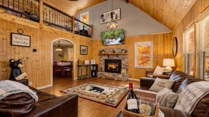 L’intérieur d’une cabane comprend une cheminée, des canapés en cuir, un coin repas et une mezzanine avec balcon.